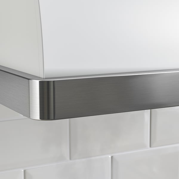 Stainless steel and white kitchen hood is mounted against a white tiled wall. The sleek metal trim highlights its modern design.