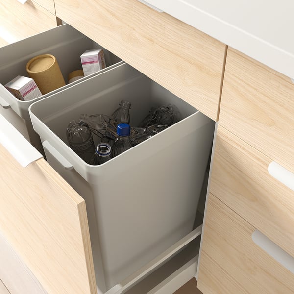 A kitchen cabinet with open drawer, featuring a HÅLLBAR bin for waste sorting, made from recycled plastic and designed for easy cleaning.