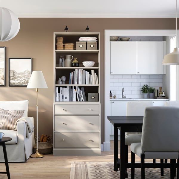 Modern living room with HAVSTA storage unit holding books, sofa, small dining table & lamp, warm lighting.