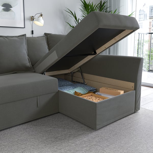 Grey sofa with open storage compartment showing blankets and books, ideal for extra space and organisation.