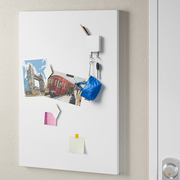 Small magnet organiser on a metal door. Holds photos, notes, keys, and a pen. Organises small items neatly.