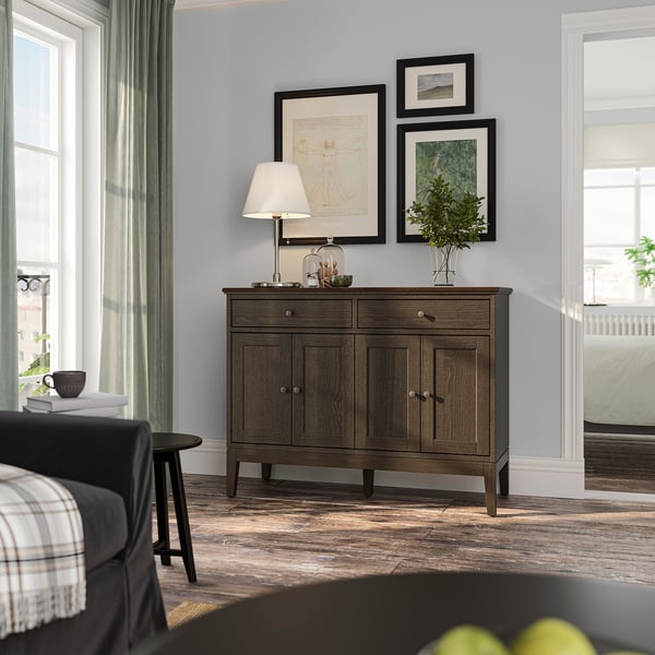 Modern room IDANÄS sideboard with bifold doors and decorative art frames. Soft lighting, dark wood, calm decor.