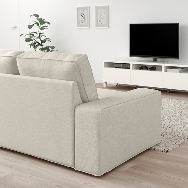 Modern living room with light grey KIVIK sofa, large flat screen tv on white stand, plant, and abstract wall art.