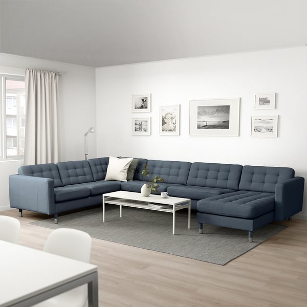 Modern living room with large blue l-shaped sofa, white coffee table, and wall art.