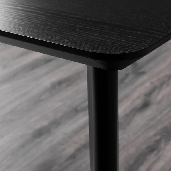 Close-up of sturdy, black wooden table edge, showcasing smooth, even finish and durable construction.
