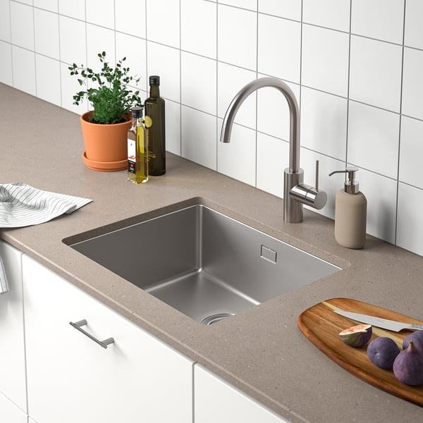 Modern kitchen sink with stainless steelLOCKEBO sink, tap, and countertop. Plant, bottle, soap, and cutting board with figs beside it.