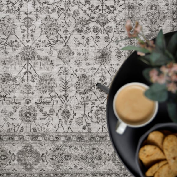Stylish rug with intricate floral pattern, coffee cup, snacks, and plant on modern table.