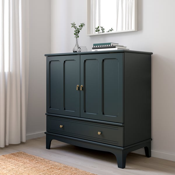 Dark green LOMMARP cabinet with gold hardware. Two doors, one drawer, with vase and books atop.