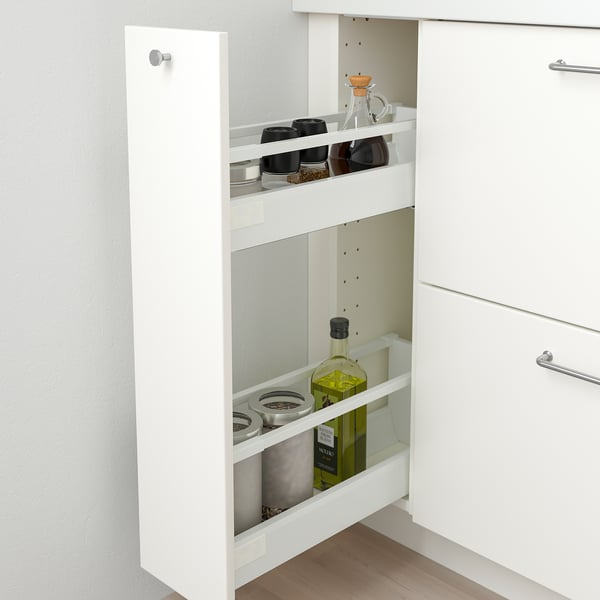 White kitchen cabinet with pull-out drawer, holding spice jars and olive oil bottle.