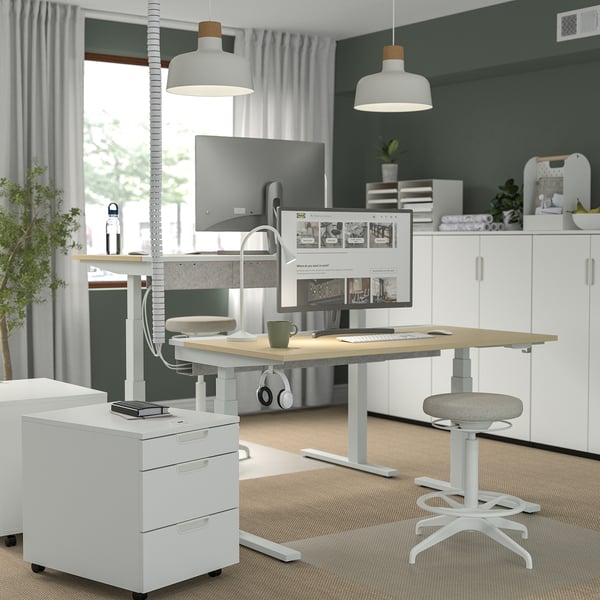 Modern home office: MITTZON white sit-stand desk, large, sleek design, dual monitors, ergonomic chair, green walls, big window.
