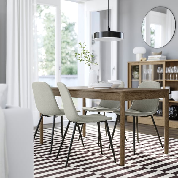 Modern dining setup with grey NORDMANSSKÄR chair, table, rug, pendant light, and large window.