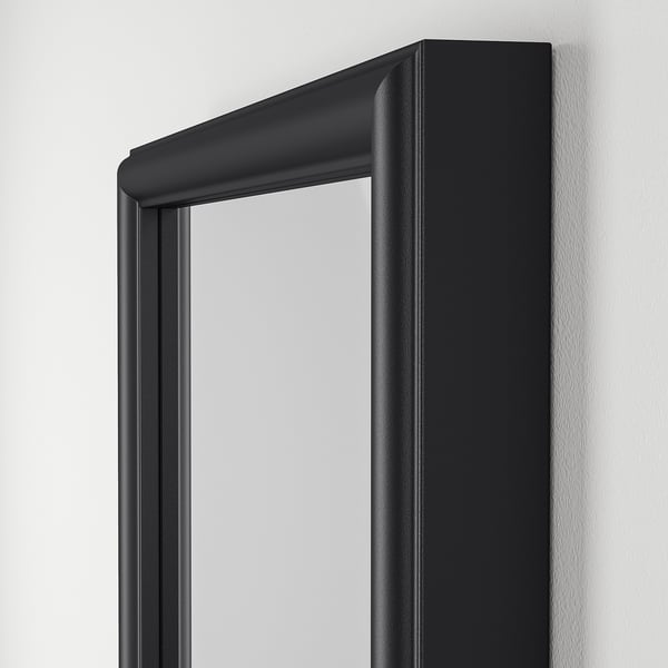 Black-framed mirror on white wall; shows quality and design detail.