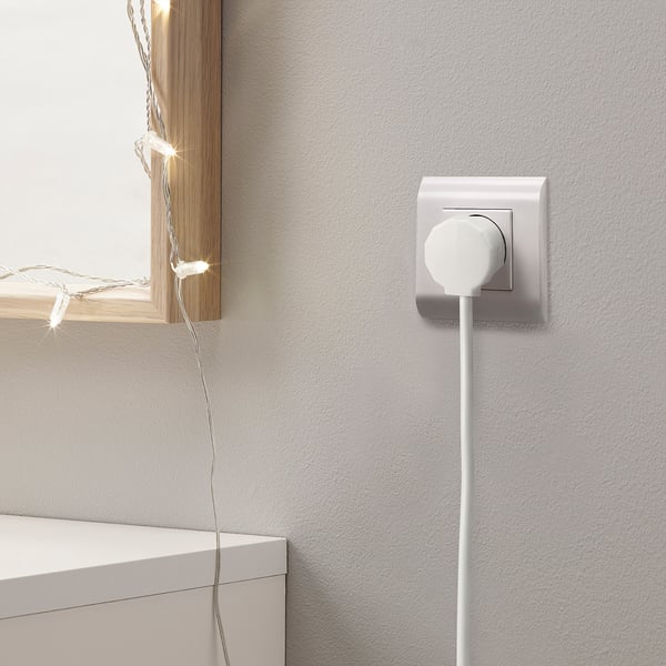 White power outlet with NYTTIG plug, wire, and lit lights.