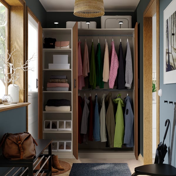 Open wardrobe with clothes, shelves, and storage boxes. Hanging garments visible, organised by colour.