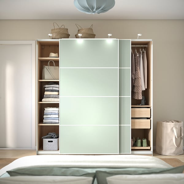 Modern bedroom with green PAX wardrobe, sliding doors, open sections, and storage.