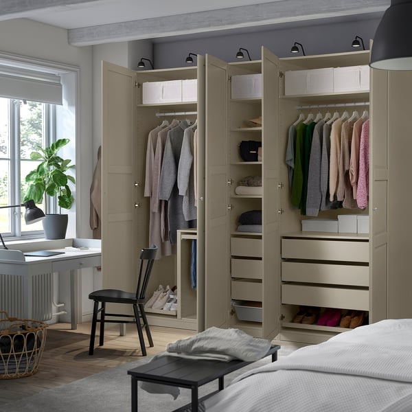 Well-organized bedroom with PAX wardrobes. Clothes hang neatly in open sections, and drawers hold folded items. Lighting inside for clear visibility.