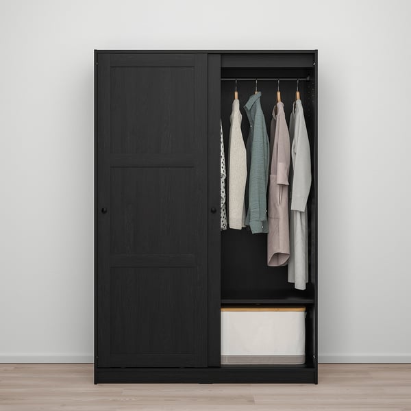 Black wardrobe with sliding doors saves space. Hangs clothes and has storage below.