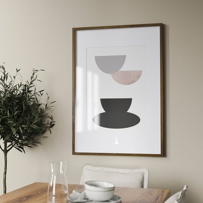 Framed abstract art hangs on a wall above a wooden table with a plant and a cup. The frame can hang vertically or horizontally.