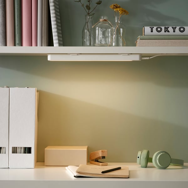 Minimalist workspace ROLFSTORP lamp, small, slim, affixed near books, subtle lighting.