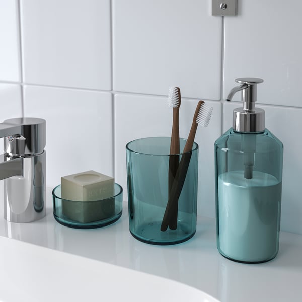 Bathroom set including soap dispenser, toothbrush holder, and tray displayed on a white countertop. The items are teal and organised neatly.