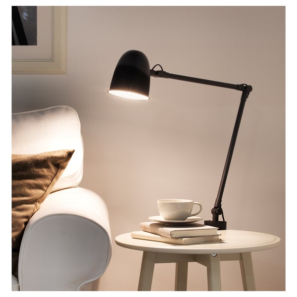 SKURUP lamp on table beside white chair, modern design.