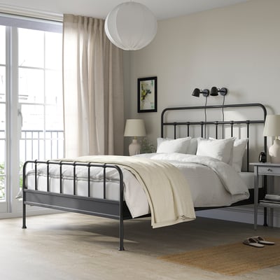 Modern bedroom with STJÄRNÖ bed, white linens, large window, bedside table, lamp, rug, painting.