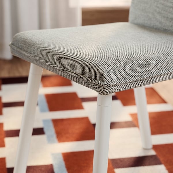 Modern dining chair with sleek white legs, grey tweed seat, and plush padding, exuding high-quality comfort and style.