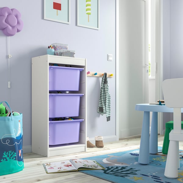 Childrens room with white TROFAST storage unit, purple bins, and toy table. Colourful decor, rug, and toys.
