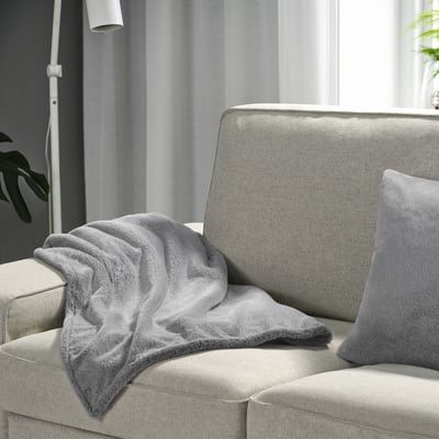 Cosy grey ULLGRIMMIA blanket on light couch, soft & recycled polyester.