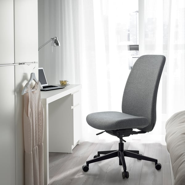 Grey VALLFJÄLLET office chair in minimalist workspace with laptop & lamp.