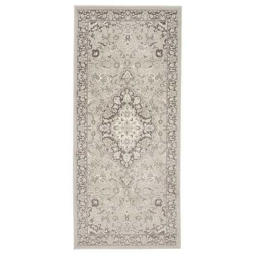 A grey VEDBÄK rug with a floral pattern. It is rectangular and made of polypropylene.
