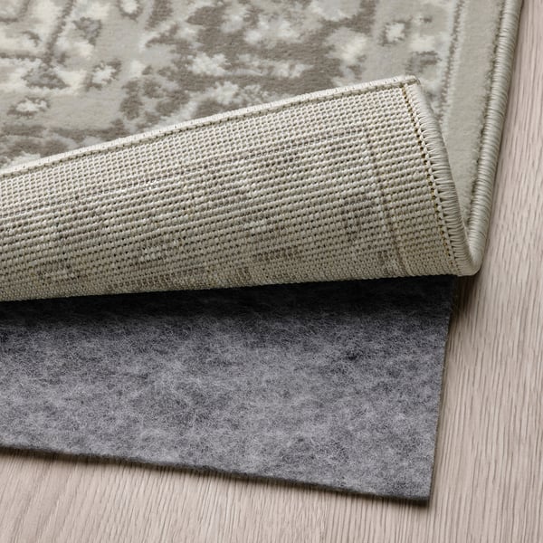Grey patterned rug with an anti-slip underlay on wooden floor.