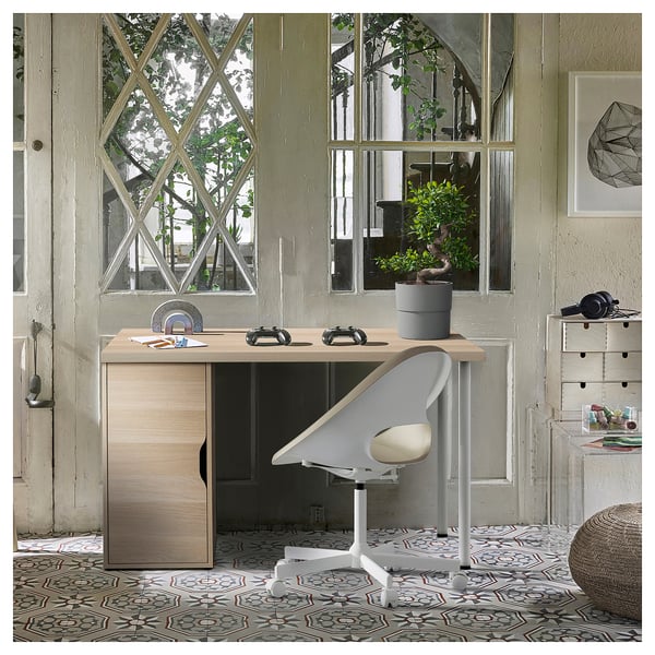 Neat home office with ALEX desk in light wood, white chair, potted plant, geometric windows, patterned rug.