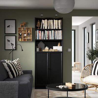 Modern living room: green walls, bookcase, grey sofa, coffee table, stylish lamps.