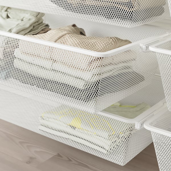 White mesh drawers on wooden floor, storing folded clothes, neatly organised.