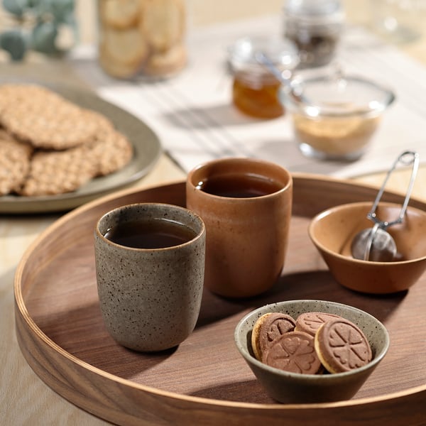GRÅRÄV cups in grey/brown on wooden tray with cookies.