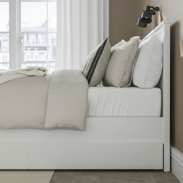 Neat bedroom featuring white GULLABERG bed with slatted design, pillows, and side light.
