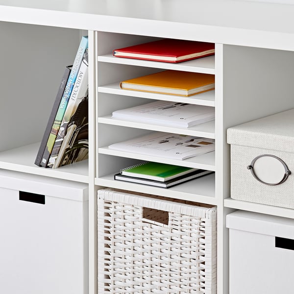 White KALLAX shelf with books and basket. Four additional shelves hold notebooks and folders, showcasing organised storage.
