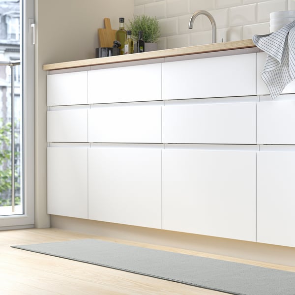 Kitchen with white drawers, sink, and grey KÖRFÄLT mat.