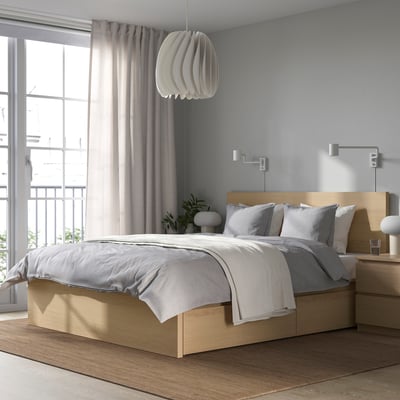 Bright, modern bedroom with a large, light wood MALM bed, grey linens, sleek bedside table, and large window with sheer curtains.