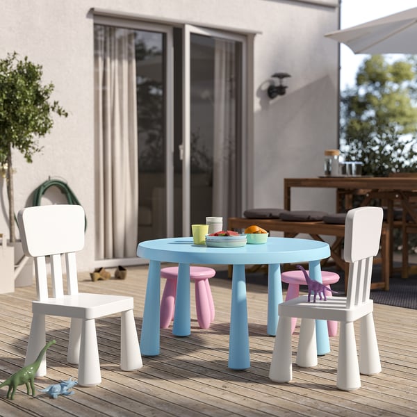 Childrens play set with blue table, 4 white/pink chairs, plastic, compact, outdoor suitable. Dinosaurs on floor, food on table.