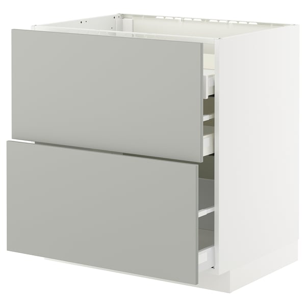 White METOD kitchen unit with light grey drawers and shelves.
