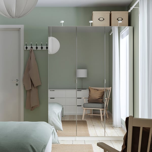 Minimalist bedroom with mint walls, mirrored wardrobe, a bed, and a chair, natural light, beige accents.