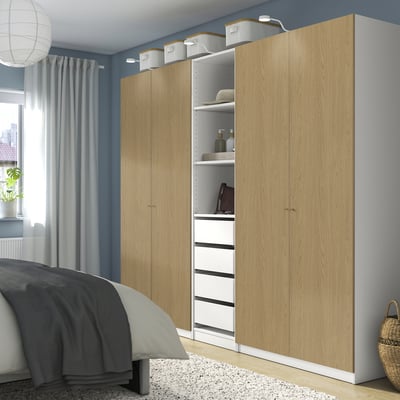 Large wooden PAX wardrobe with open shelves and drawers in bedroom. Dark blue walls, grey curtains.