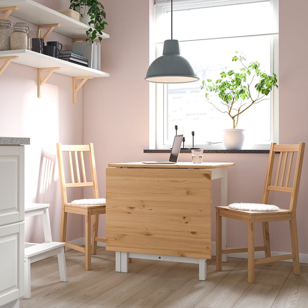 Cosy IKEA kitchen with pink walls, plants, and minimalist design.