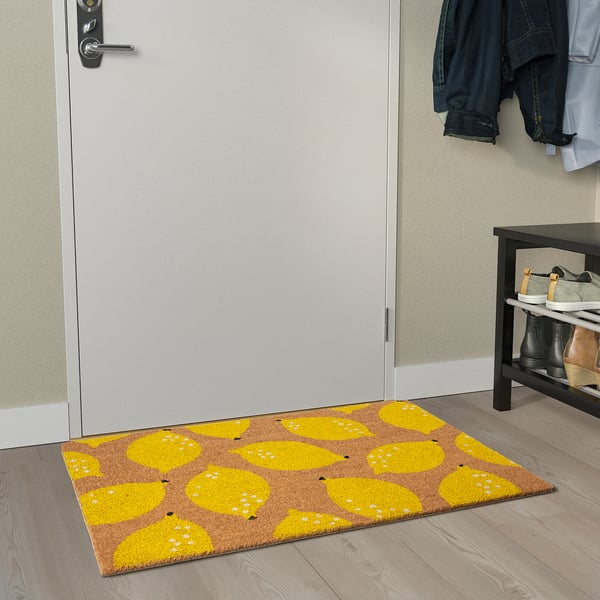 Bright yellow lemon-patterned doormat brightens entrance, placed near a door.