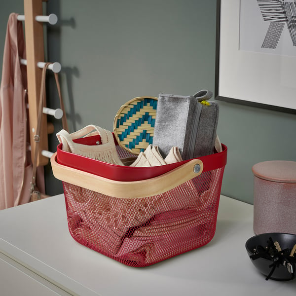 Red mesh storage basket with wooden handles holds woven tray and fabric items, ideal for organising various items indoors.