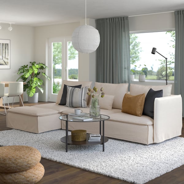 Modern living room with large SÖDERHAMN beige sectional sofa, glass coffee table, and large windows for a bright atmosphere.