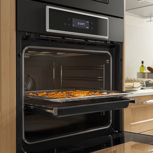 A modern oven with air fry function displays baked sweet potatoes on a tray, showcasing its crispy capabilities.