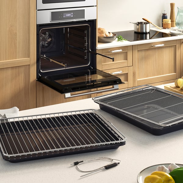 Modern kitchen scene featuring an open IKEA STENABY oven with air fry accessories laid out on the countertop.